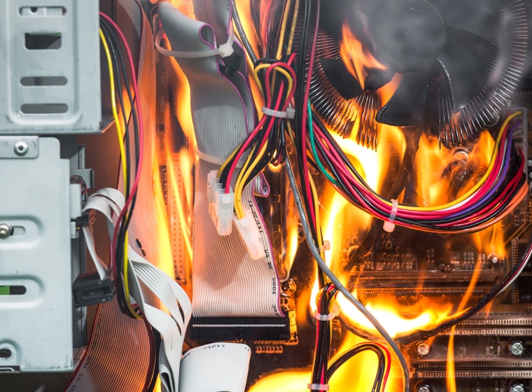 A computer tower and circuit boards are engulfed in flames. Exponent electrical engineers construct detailed accident reconstructions.