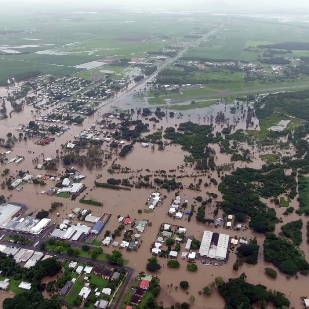 Aerial view of small town flooded with water after a storm with green fields in background 