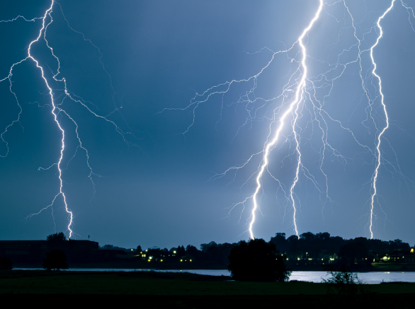 Lightning strikes community of homes in distance at night 