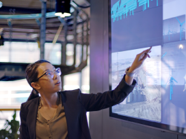 A scientist points to large screens and explains data