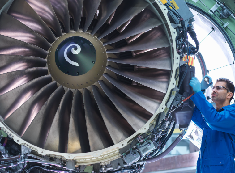 Aviation mechanic standing next to a large jet engine. Exponent provides aeronautical engineering expertise.