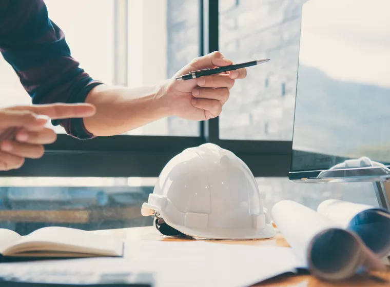Construction consultant in an office meeting on cell phone, Exponent project management and schedule audits.