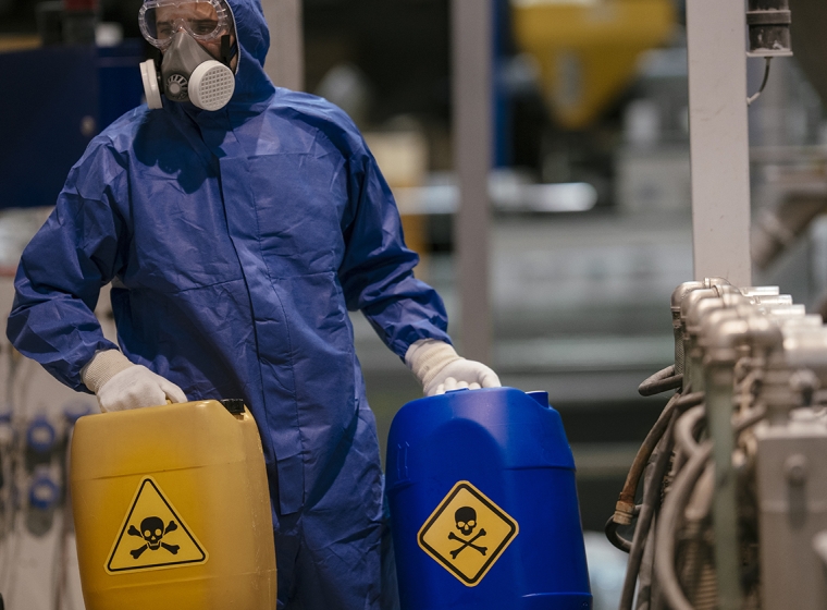 Worker handles hazardous materials. Exponent consultants provide technical expertise for chemical safety and compliance.