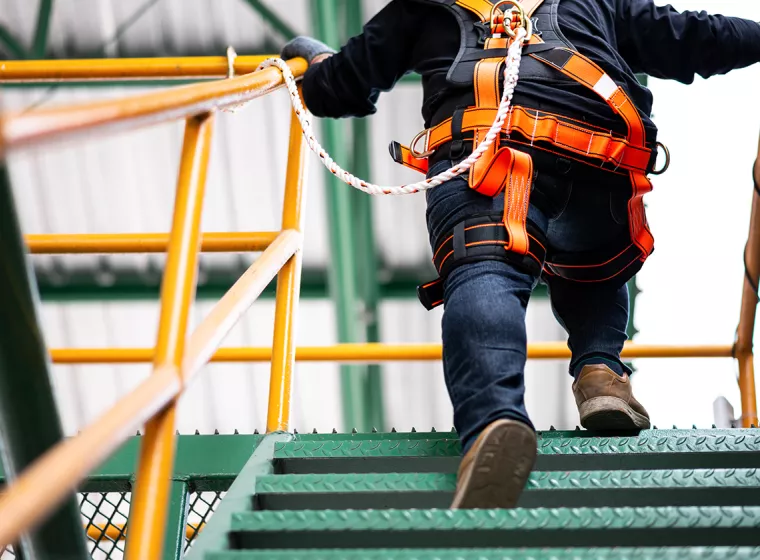 Worker in bright color safety gear running up steps. Exponent conducts construction risk analyses.