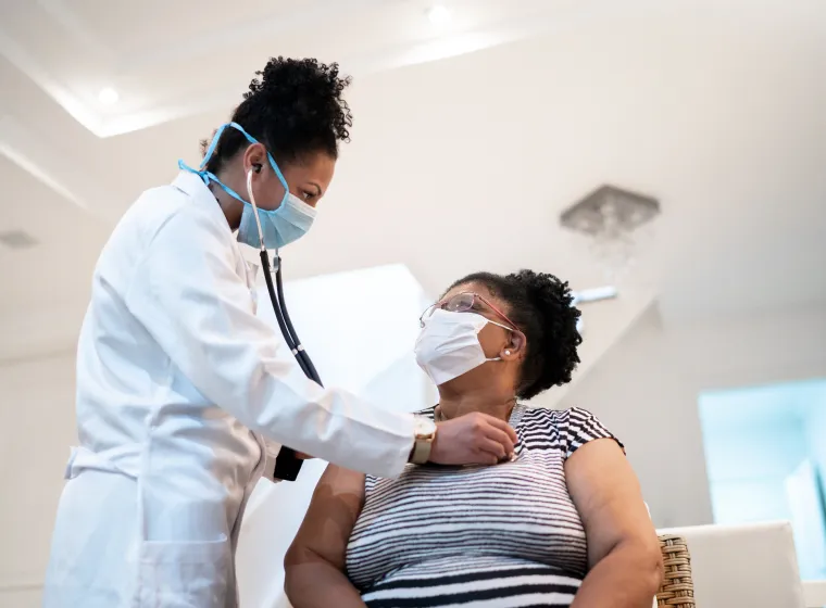 Doctor listening to patient's heartbeat during home visit