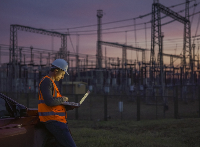 Electrical utility worker in the field, entering data into a tablet. Exponent's risk assessments improve efficiency and mitigate risks. 