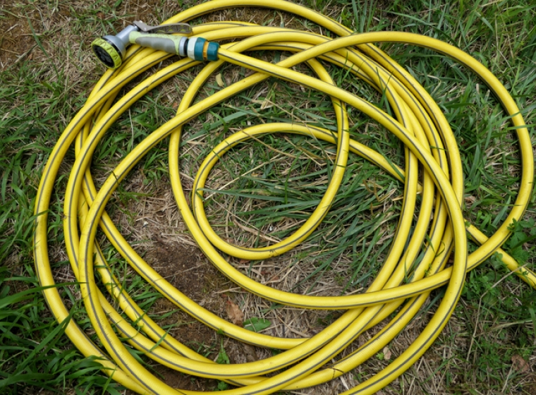 Coiled garden hose in the grass. Exponent helps manufacturers improve safety, innovation and performance of household products.