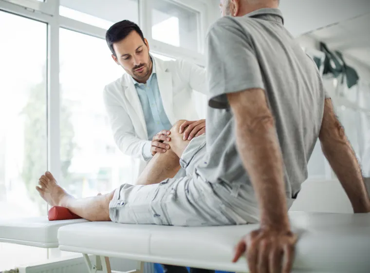 Senior man having his knee examined by a doctor.