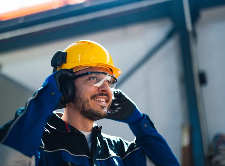 Smiling Worker in Safety Helmet Communicating in Factory