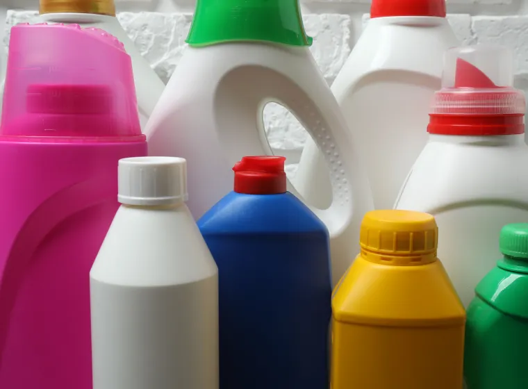  House cleaning supplies on a wooden table against a brick wall background 