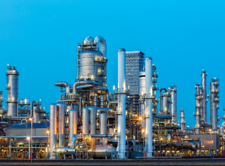 Oil refinery with bright lights at dusk. Exponent provides energy engineering expertise to improve refinery safety and efficiency.