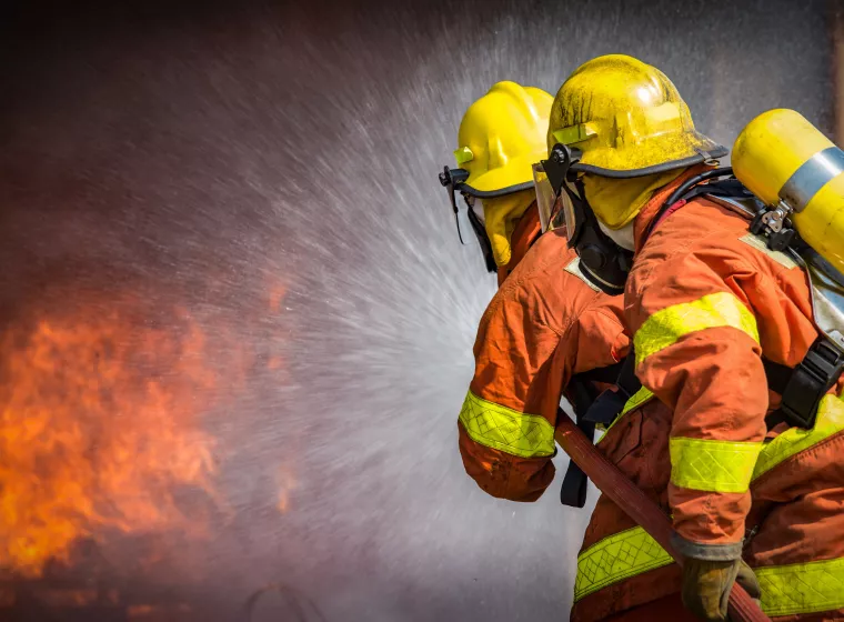 2 firefighters spraying high pressure water to fire