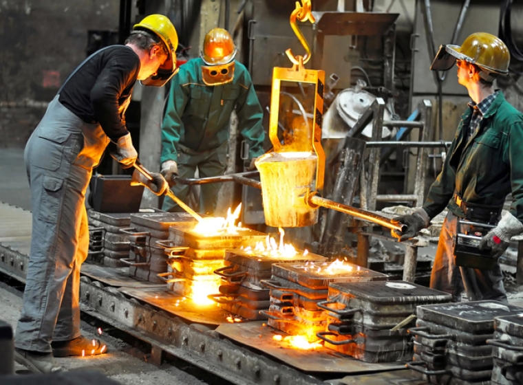 Workers in a steel foundry wear hard hats and protective gear. Exponent helps improve industrial operations.