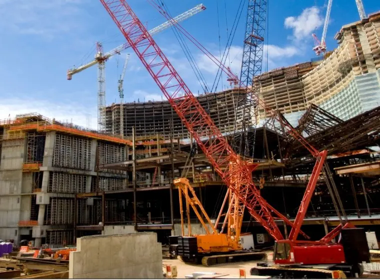 Two construction cranes on a large work site