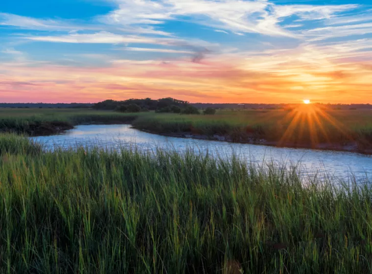 A sunset over a river landscape. Exponent helps companies understand and mitigate their impact on the environment.