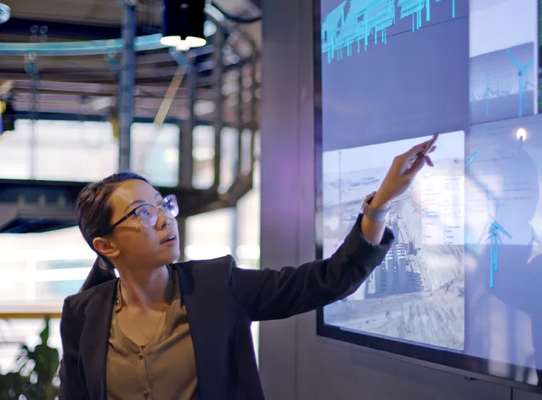 A scientist points to large screens and explains data
