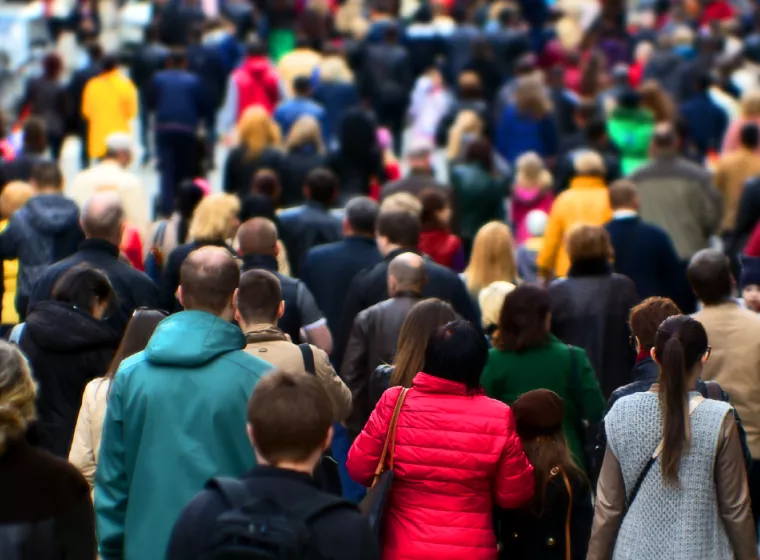 Crowd of people wearing coats and walking on sidewalk. Exponent conducts epidemiological and biostatistical research.