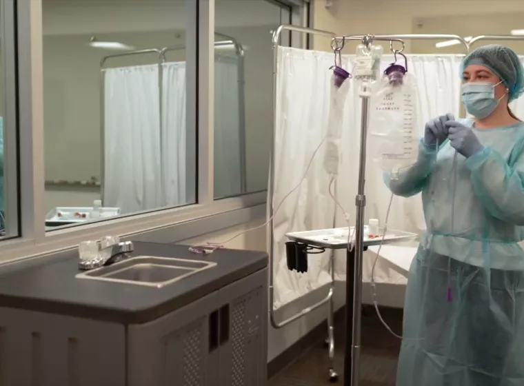 medical personnel hanging an iv bag wearing ppe