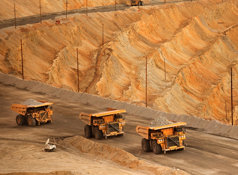 Large dump trucks hauling raw material from a surface mine. Exponent helps maximize efficiency and safety of surface mining.