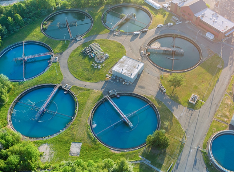 Aerial view of water treatment facility, large circular water holding tanks. Exponent engineers help stakeholders improve wastewater management.