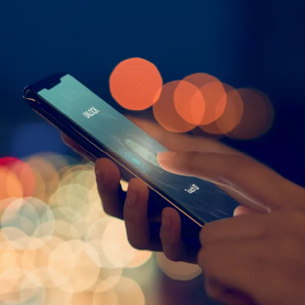 Hands holding a smartphone and unlocking it with fingerprint ID