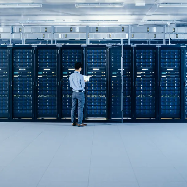 In the Modern Data Center: IT Engineer Standing Beside Open Server Rack Cabinets, Does Wireless Maintenance and Diagnostics Procedure with a Laptop.