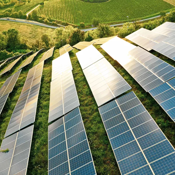 Multiple solar panels placed throughout a grassy field on a hill