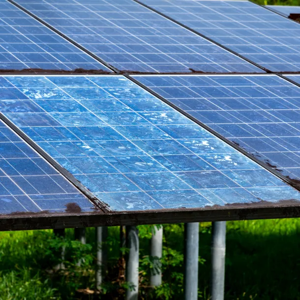 Close-up of weathered solar panels with faded blue cells and surface degradation. Concept of renewable energy maintenance and efficiency loss over time.