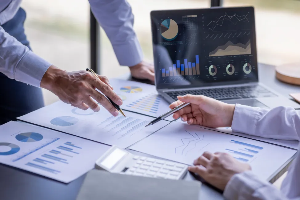 Team businesspeople or an accountant team are analyzing data charts, graphs, and a dashboard on a laptop screen in order to prepare a statistical report and discuss financial data in an office. - stock photo