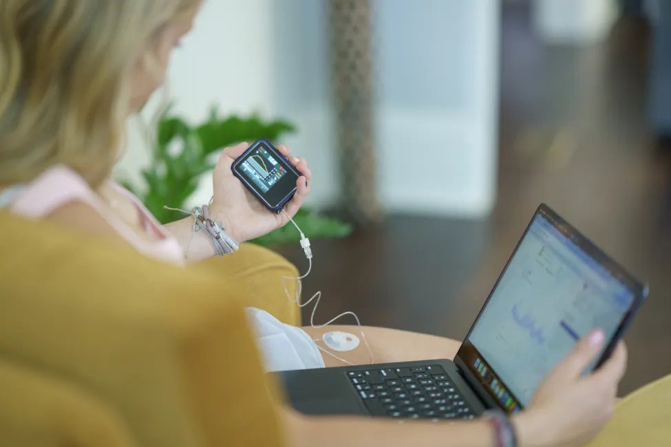 A woman uses advanced technology to monitor personal health metrics on electronic devices, showcasing innovation in healthcare and self-awareness.
