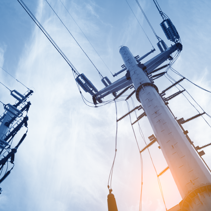 View of two utility poles and wires from the ground against a clear blue sky