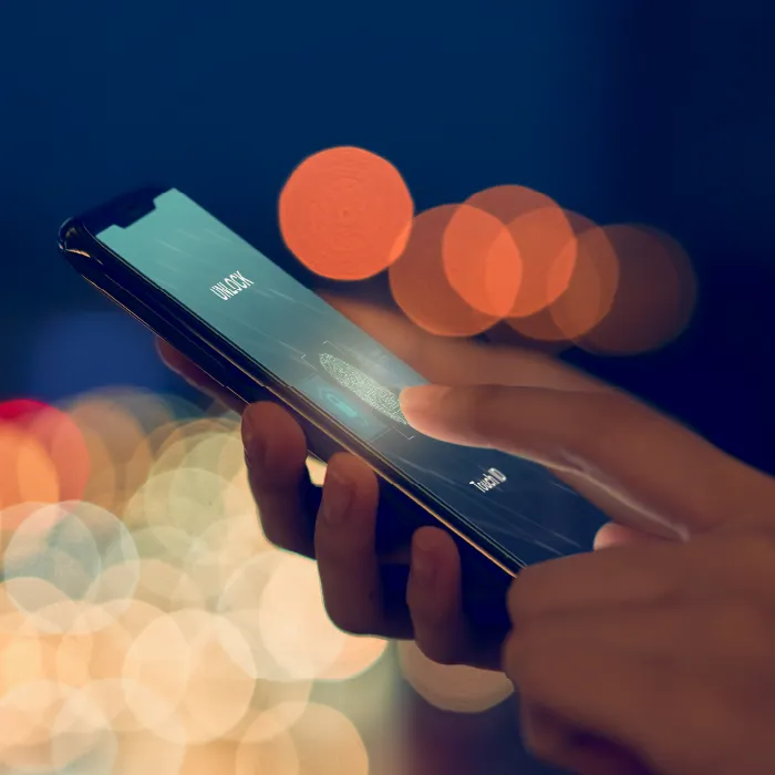 Hands holding a smartphone and unlocking it with fingerprint ID