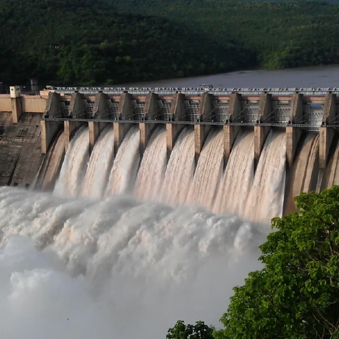 A large power generation dam, water rushing through open concrete gates on a river. Exponent utility and industrial power consulting.