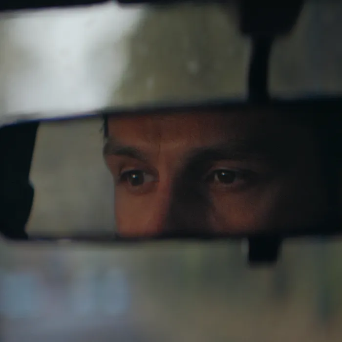 Rear mirror view. Sleepy, tired, fatigued, exhausted young man closing eyes