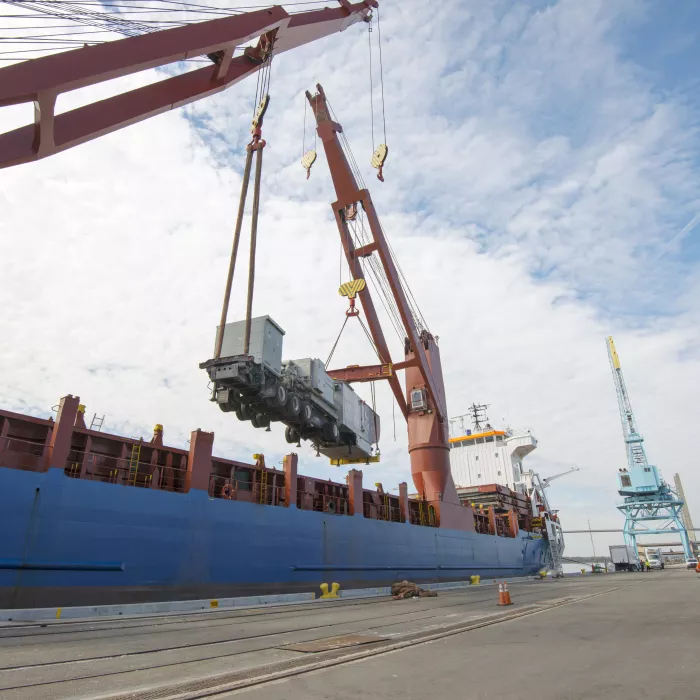 Workers unloading containers from ship in port