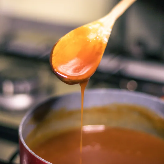 Close-up of a chef's hand-cooking creme caramel sauce