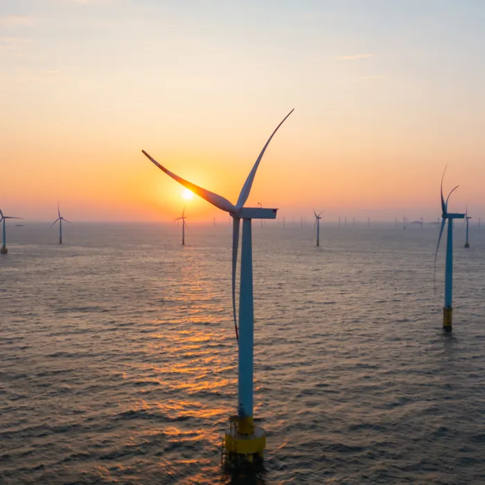 Close-up of wind turbines at sea at sunrise 