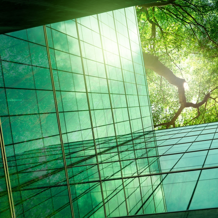 Sustainable green building. Eco-friendly building in modern city. ESG. Sustainable glass office building with green tree. Corporate sustainability. Net zero emission.