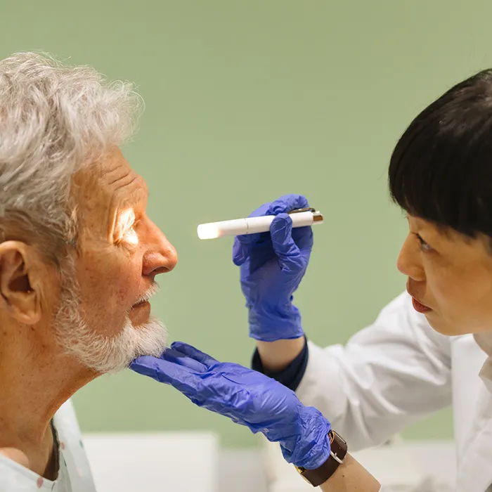 Doctor looking in patient’s eyes with an ophthalmoscope