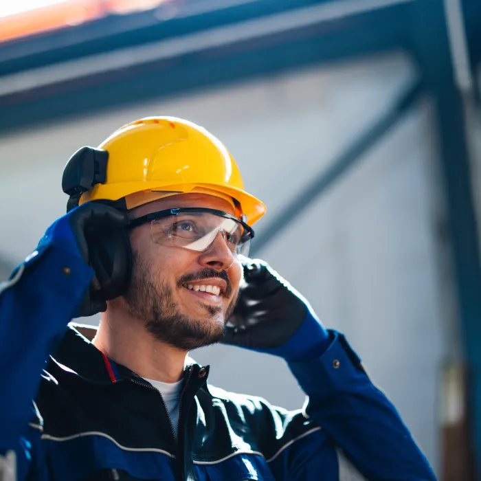 Smiling Worker in Safety Helmet Communicating in Factory