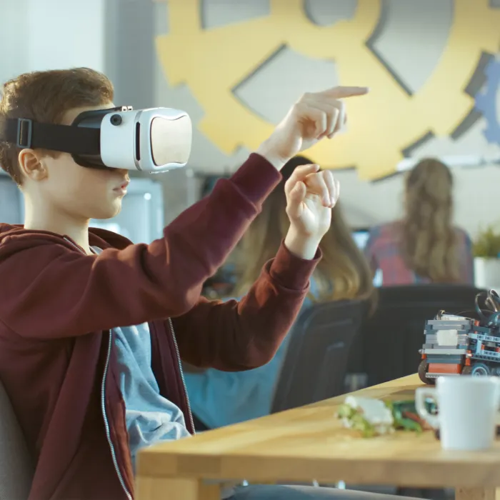 In a Computer Science Class Boy Wearing Virtual Reality Headset Works on a Programing Project