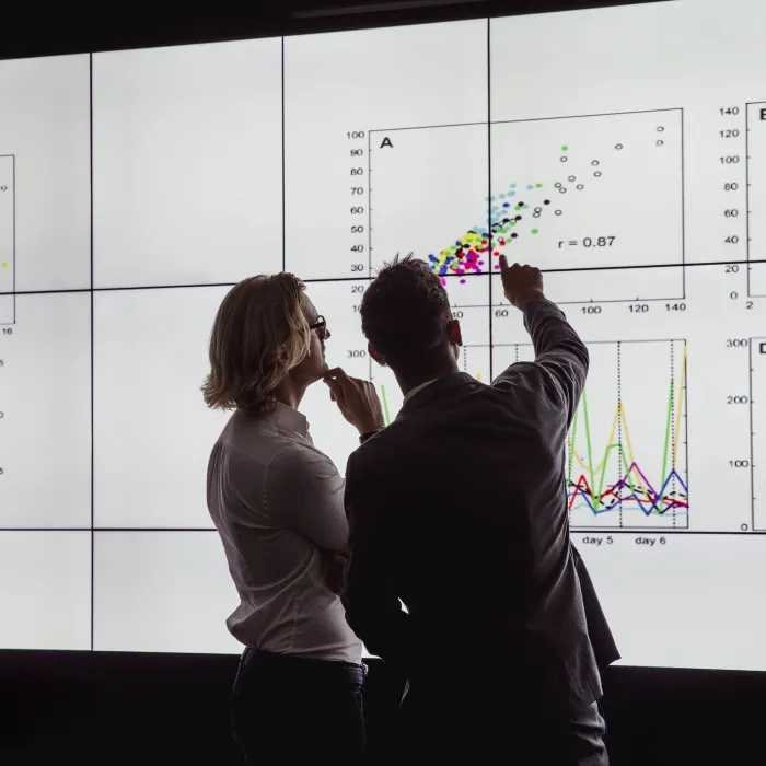 Business men in a dark room standing in front of a large data display