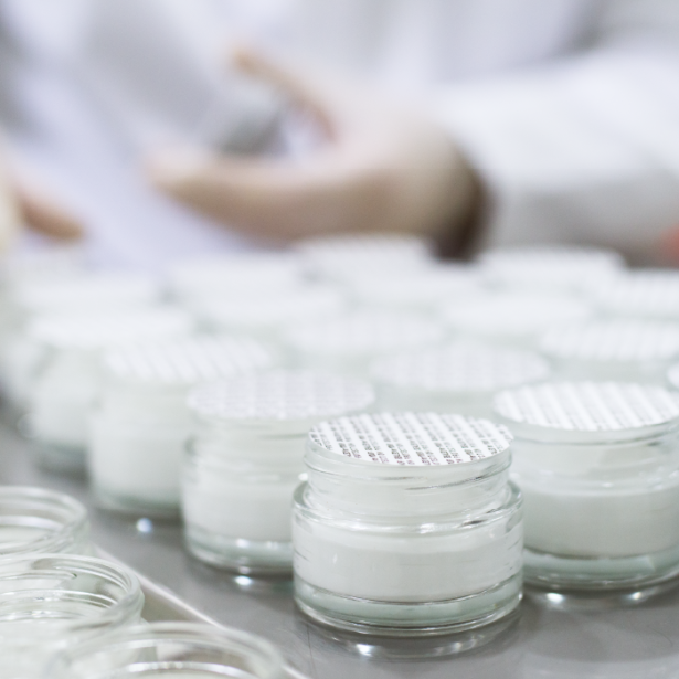 Cosmetic product in a glass jar being sealed by hand