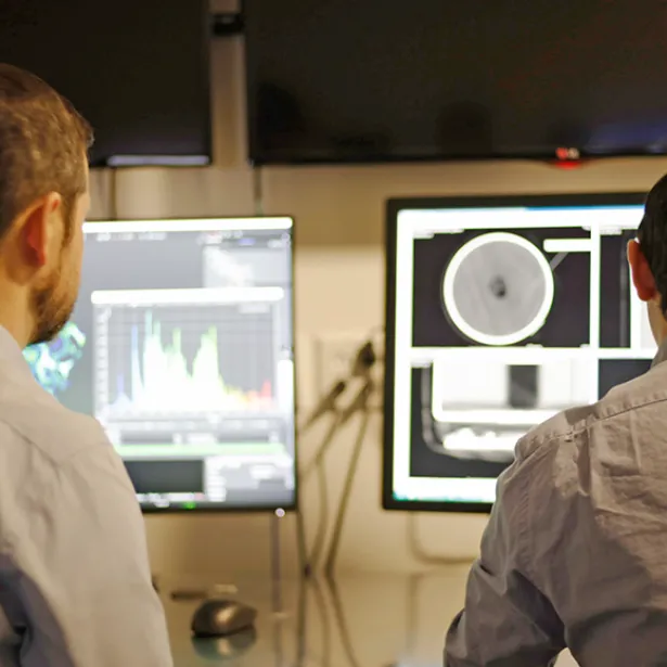 Worker scans images and videos on computer screens. Exponent engineers provide support for computer control systems.