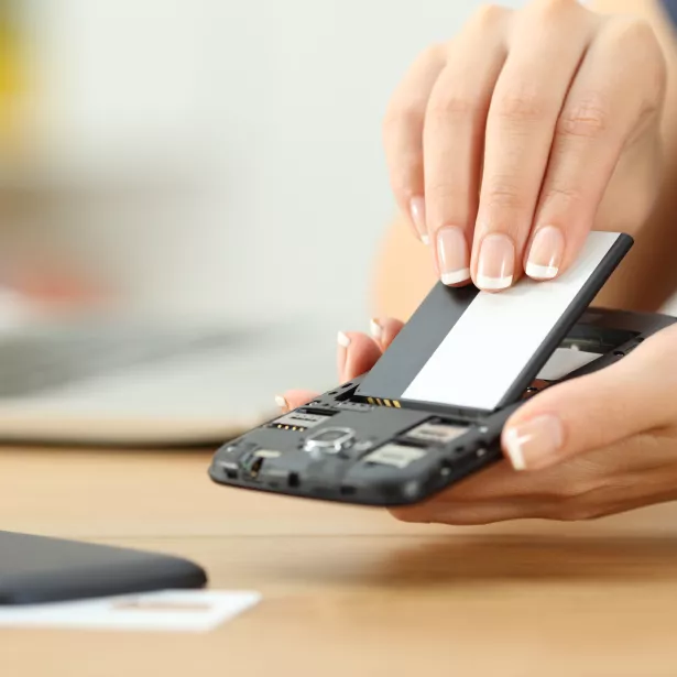 Hand putting a battery into a smart phone