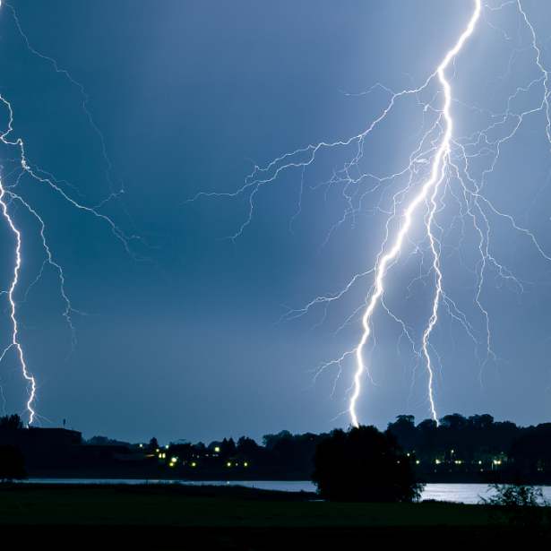 Lightning strikes community of homes in distance at night 