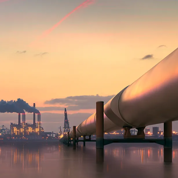 Oil pipeline stretching over the ocean with city background. Exponent helps improve efficiency and safety of oil and gas pipeline.