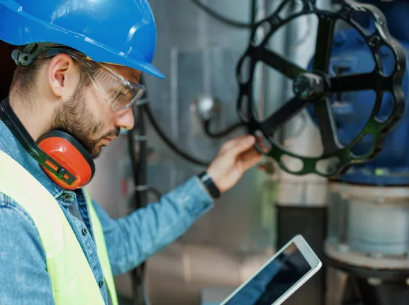 Person inspecting Oil and Gas Infrastructure while review notes on a tablet