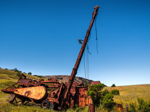 Rusty abandoned well and equipment in the middle of a hillside field