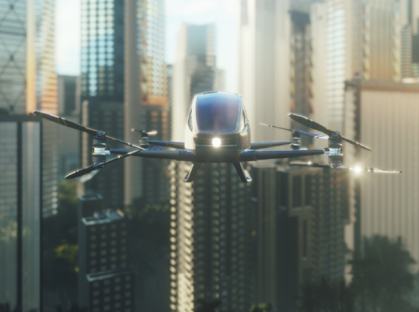 A black, futuristic-looking electric helicopter hovering over a city